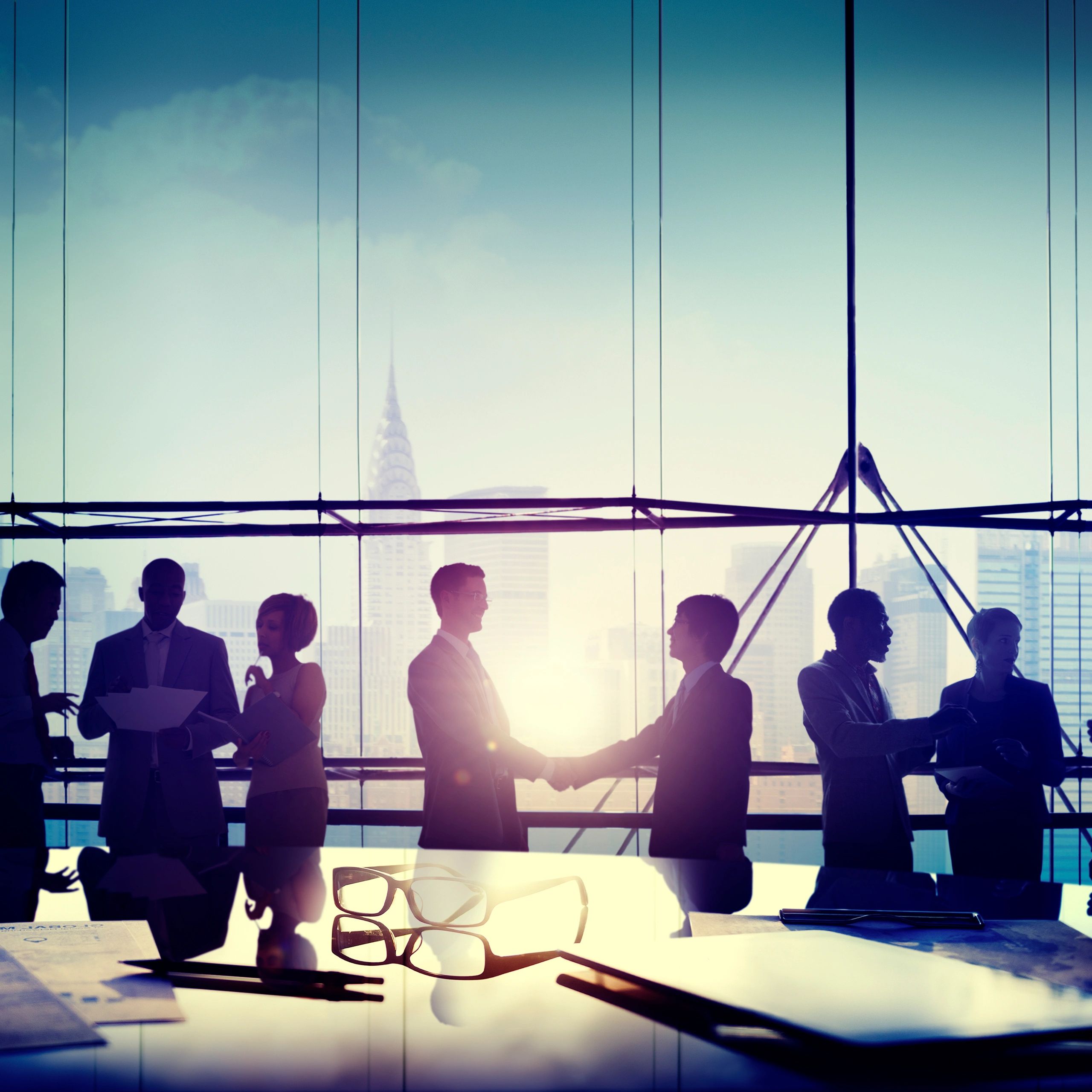 Silhouetted business group in high-rise office with cityscape